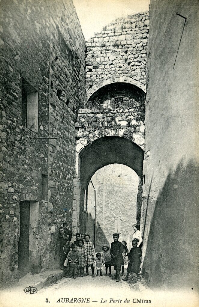 Carte postale ancienne de la Porte Gachiou vue de la rue du Château. Une famille pose devant la porte - Agrandir l'image, fenêtre modale