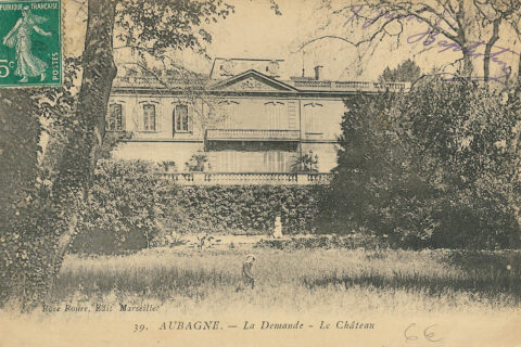 Au premier plan le jardin où pose une jeune femme, au second plan la façade du château en hauteur par rapport au jardin.