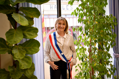 Danielle Menet dans la salle Paul Dol, au milieu de plantes vertes, devant une fenêtre - Agrandir l'image, fenêtre modale