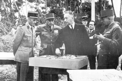 Le Ministre et le colonel discutent debout autour d'une maquette. - Agrandir l'image 1 sur 2, fenêtre modale