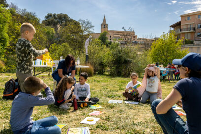 Des enfants assis sur l'herbe du parc des berges de l'Huveaune. Le clocher de Saint-Sauveur se détache dans le ciel d'une belle journée ensoleillée - Agrandir l'image, fenêtre modale