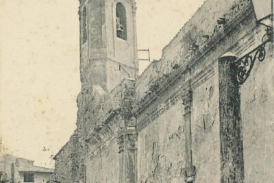 Des enfants jouent au milieu de décombres de bois. On aperçoit le mur de l'ancienne église avec des pilastres et des frises. Au fond, le clocher triangulaire. - Agrandir l'image 15 sur 18, fenêtre modale