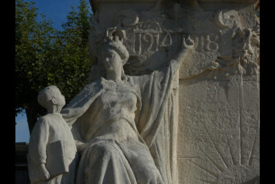 Une femme couronnée assise incarnant la République montre avec son doigt l'inscription "1914-1918" à un écolier debout à côté d'elle - Agrandir l'image 2 sur 3, fenêtre modale