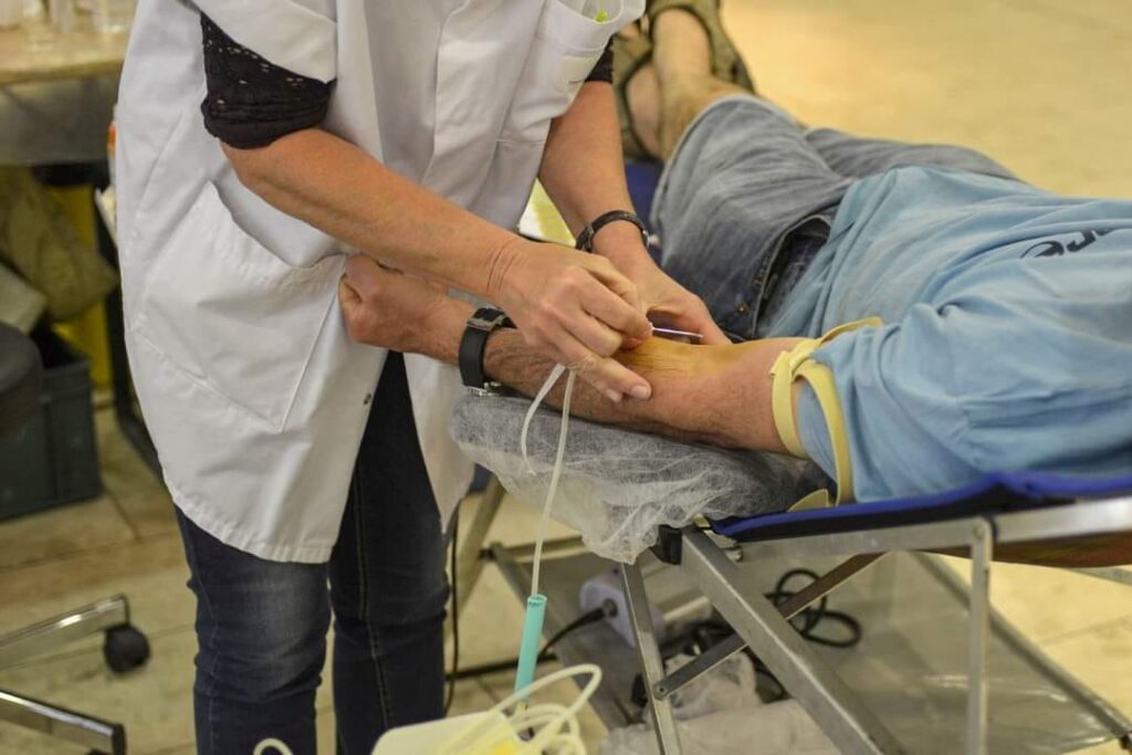 Un donneur de sang allongé, avec une infirmière réalisant la prise de sang. - Agrandir l'image, fenêtre modale