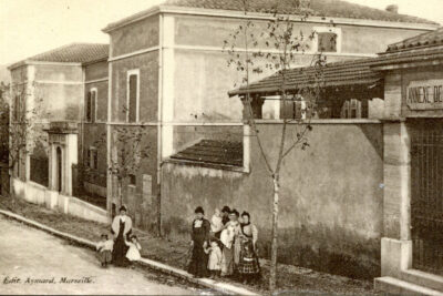 Des femmes et des enfants posent devant le long bâtiment, dans la rue - Agrandir l'image 13 sur 18, fenêtre modale