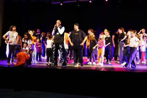 Miguel Nosibor entouré d'enfants sur la scène de l'Espace des Libertés.