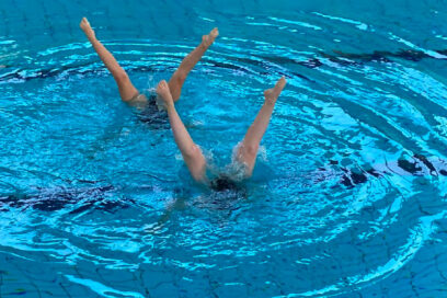 Affiche du gala de natation artistique qui aura lieu samedi 25 juin 2024 à la piscine Alain-Bernard. Les jambes de 2 nageuses sortent de l'eau, tandis que leurs têtes se trouvent sous l'eau, formant un V - Agrandir l'image, fenêtre modale