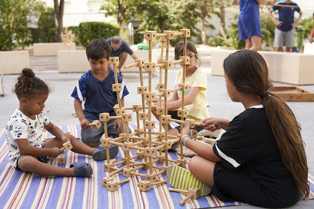 Des enfants jouent en assemblant une structure en bois.