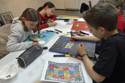 Quatre enfants sont assis à une table et participent à un atelier de graf. - Agrandir l'image, fenêtre modale