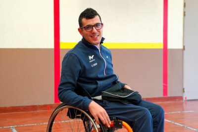 Souriant et portant un survêtement, Aurélien Fabre assis dans son fauteuil roulant, dans un gymnase - Agrandir l'image 5 sur 6, fenêtre modale