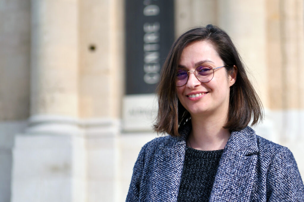 L'artiste Niloufar Basiri, avec des lunettes, souriante devant la façade du centre d'art contemporain Les Pénitents Noirs, le 19 mars 2024 - Photo Richard Guesnier - Agrandir l'image, fenêtre modale