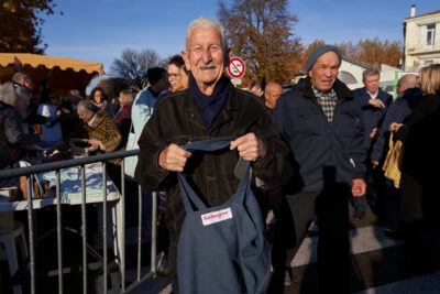 Un monsieur avec une belle moustache présente fièrement le tote bag avec un logo de la ville d'Aubagne qu'il vient de recevoir après avoir répondu à un questionnaire - Agrandir l'image 2 sur 10, fenêtre modale