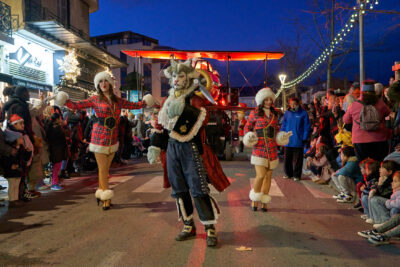 Un danseur chat et 2 danseuses aux couleurs du Père Noël précède l'avion dans lequel se trouve le Père Noël qui descend le cours Foch à l'occasion de la Parade de Noël d'Aubagne, le 22 décembre 2024 - Agrandir l'image 16 sur 27, fenêtre modale