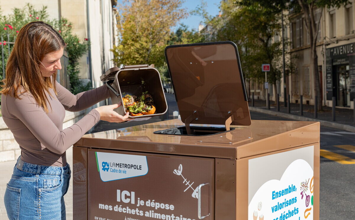 Une femme vide un seau dans une borne pour déchets alimentaires