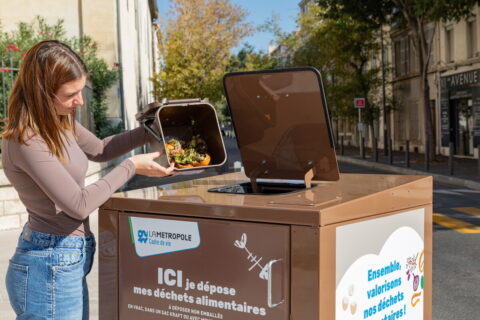 Une femme vide un seau dans une borne pour déchets alimentaires