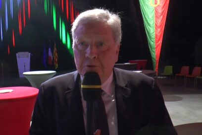 Jean-Bernard Louis en interview avec un micro à la main, devant un drapeau de la Légion étrangère - Agrandir l'image, fenêtre modale