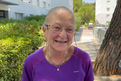 Pierrette Alberto souriante, avec des lunettes et un tricot violet, le jour de l'inauguration de sa placette au Charrel - Agrandir l'image 1 sur 11, fenêtre modale