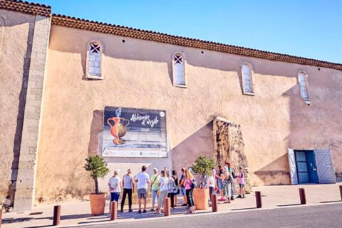 Un groupe de personnes à l'extérieur du centre d'art contemporain des Pénitents Noirs regardent l'affiche d'une exposition