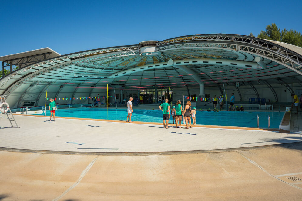 Vue large de la piscine Alain Bernard à moitié ouverte, avec des surveillants encadrant un cours d'aisance aquatique.