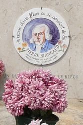 Une plaque ronde avec le portrait de Blancard avec des cheveux blancs. En dessous, un bouquet de chrysanthèmes pourpres. - Agrandir l'image, .JPG 387 Ko (fenêtre modale)