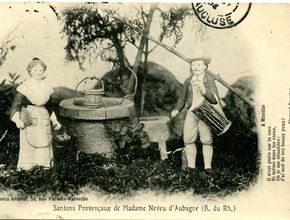 A gauche, une femme en tenue traditionnelle et à droite un tambourinaïre. Au milieu, un puits - Agrandir l'image, .JPG 1,9 Mo (fenêtre modale)
